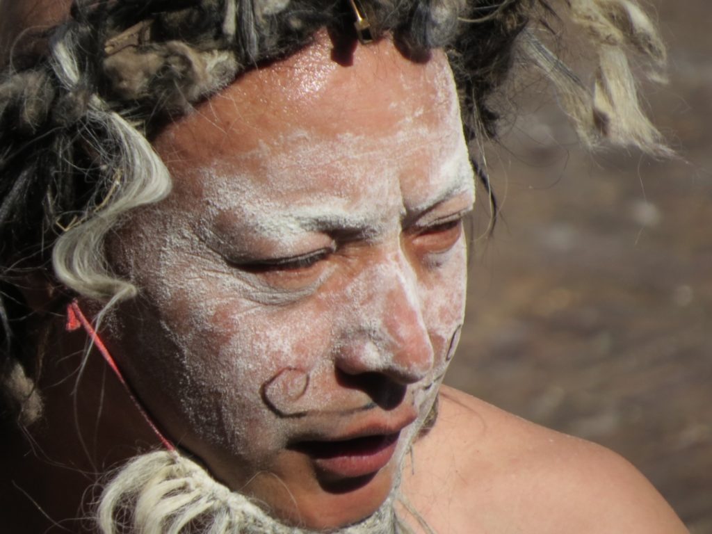Close up of man with face painted and headress made of sheep wool.