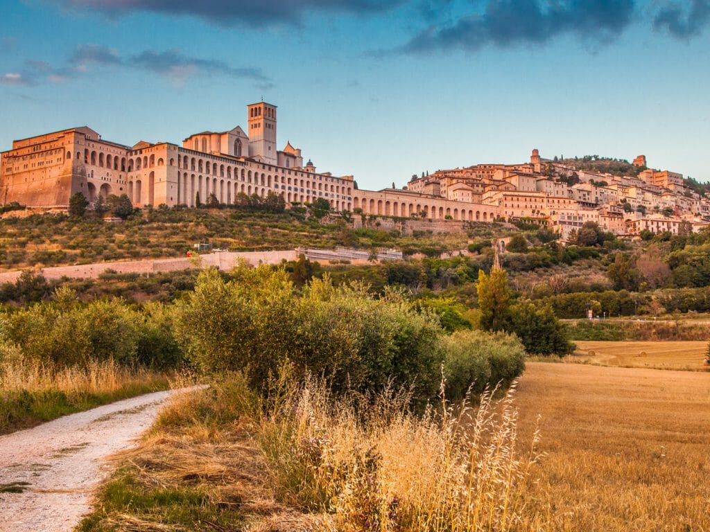 Beautiful view of the ancient town of Assisi with dramatic cloudscape in golden evening light, Umbri
