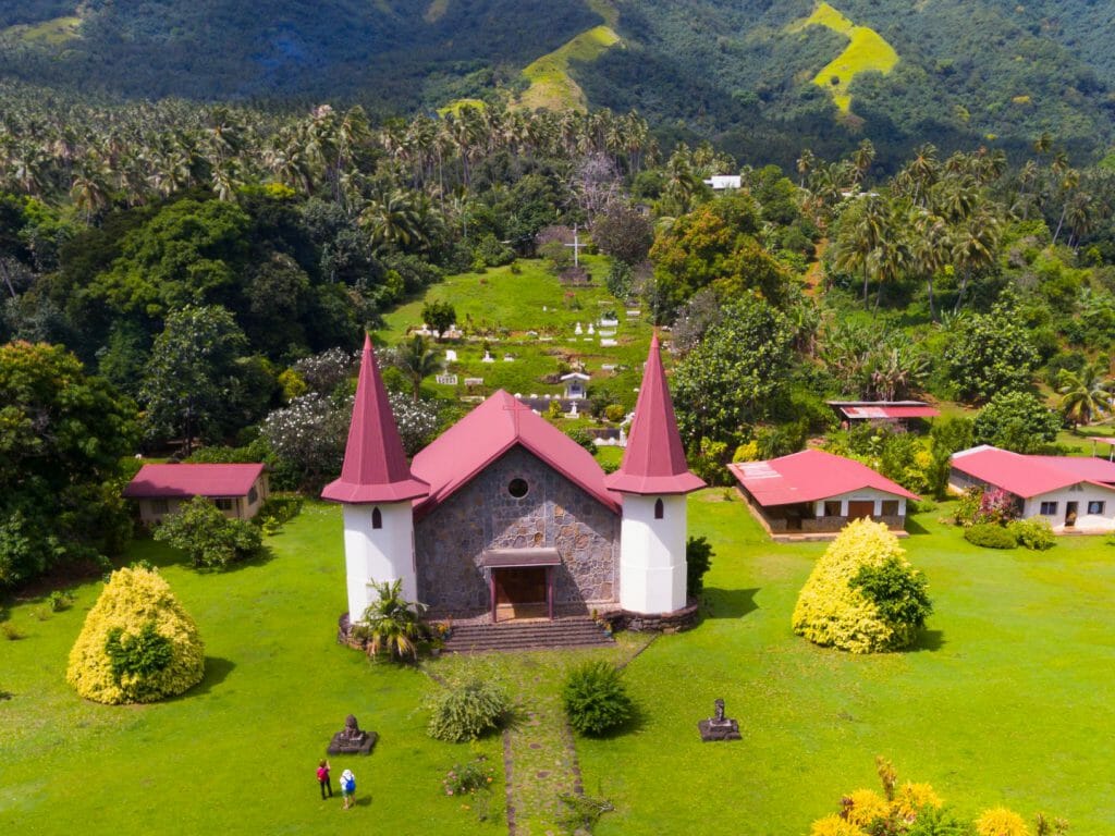 Red roofed church set amidst lush scenery.