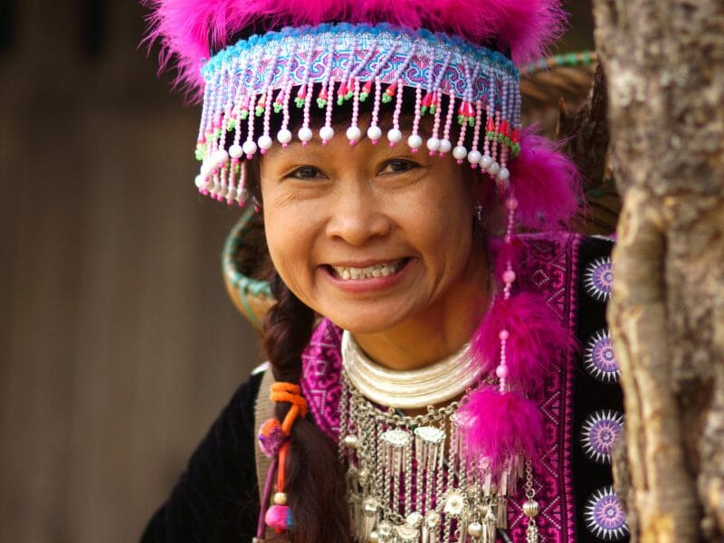 Portrait of hill tribe woman wearing colourful beaded and pink feathered headwear.