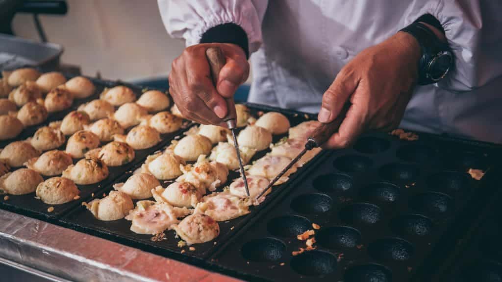Mans hands preparing Japanese snack food.