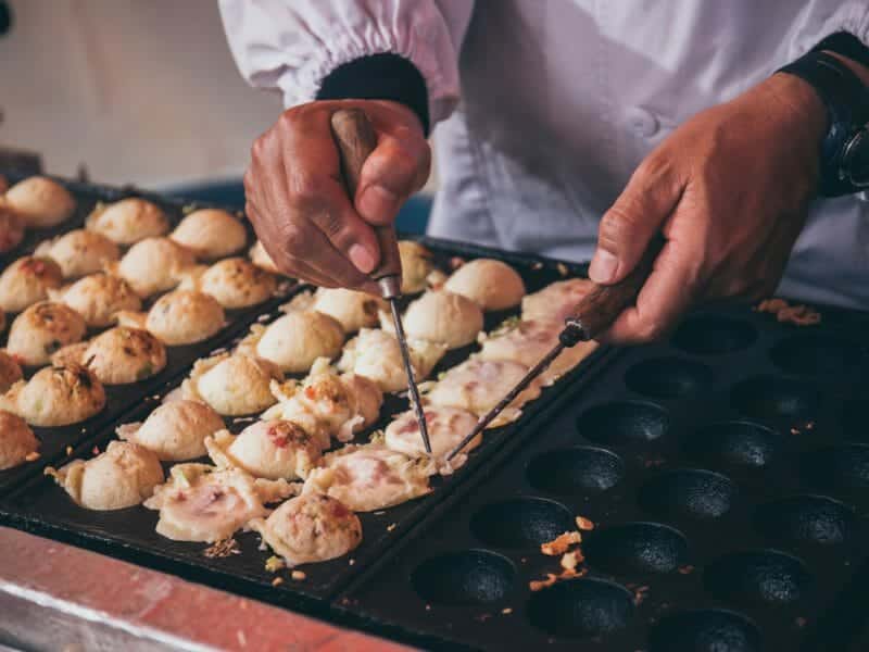 Mans hands preparing Japanese snack food.