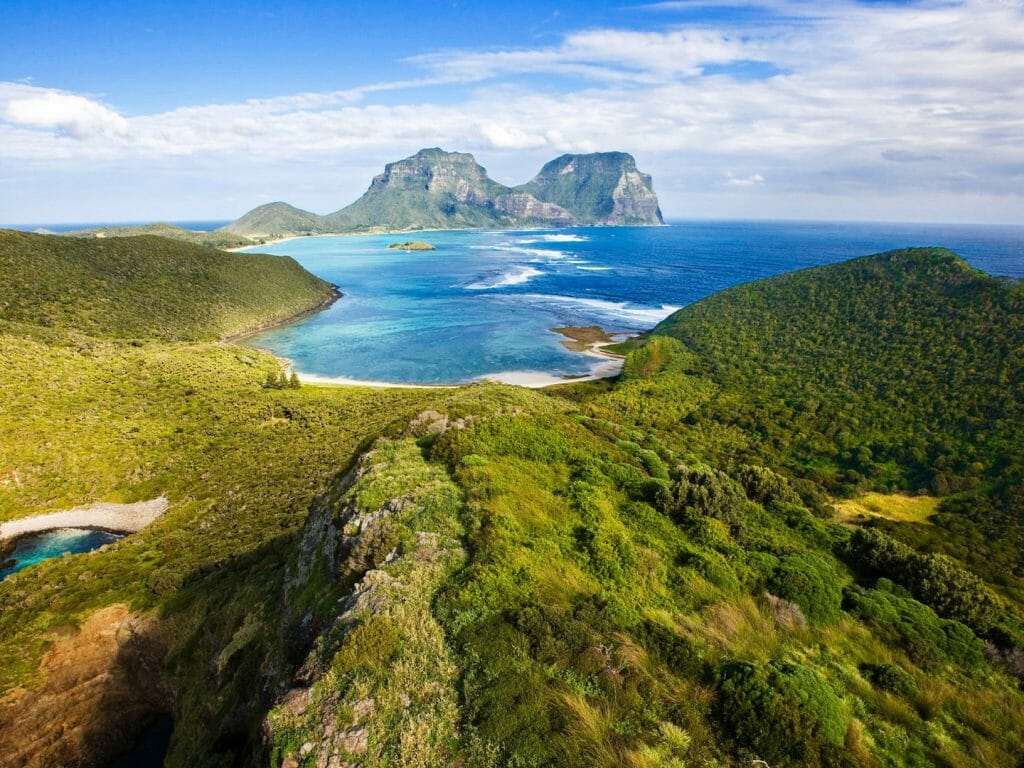 Panoramic view across the length of Lord Howe Island with greenery in foreground to Mount Gower in distance.