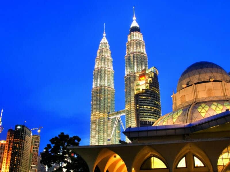 Looking up at Petronas Towers lit up at night.