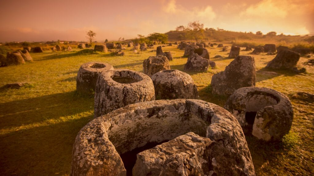 View of ancient jar shaped rocks covering a plain at sunrise.
