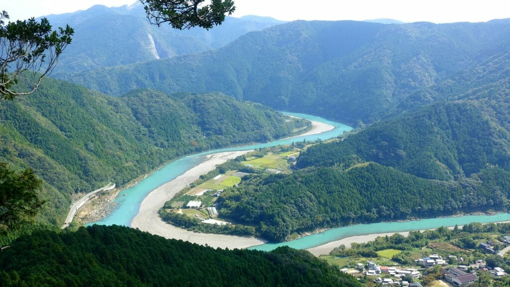 Panoramic aerial view of bending river weaving through lush hills.