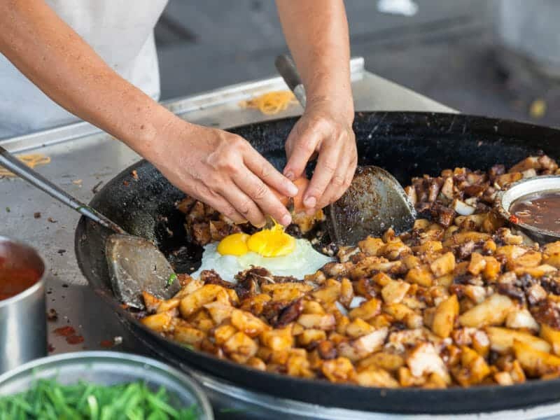 Large pan of food being cooked in a market.
