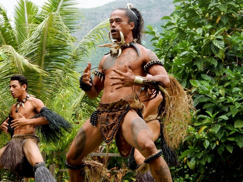Mean wearing traditional costumes performing ritual Polynesian dance.