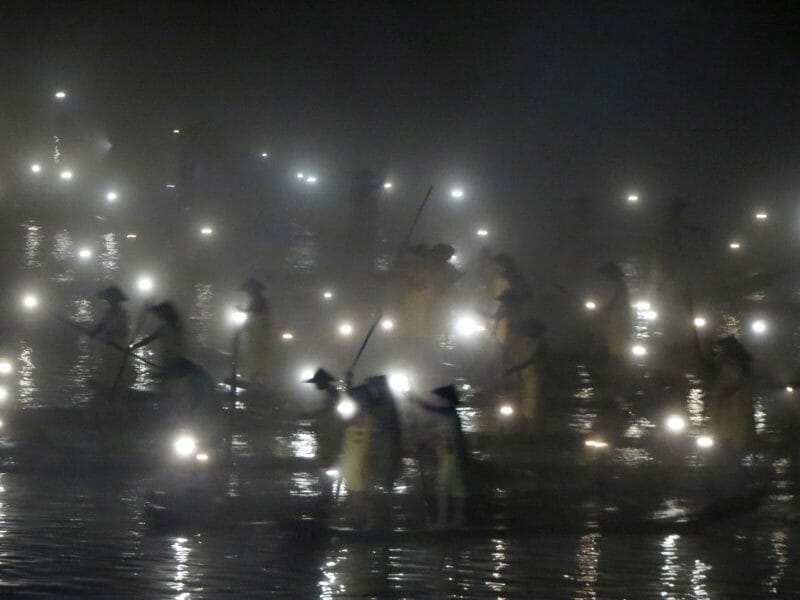 Black and white image of traditional fishermen silhouetted in a light show.