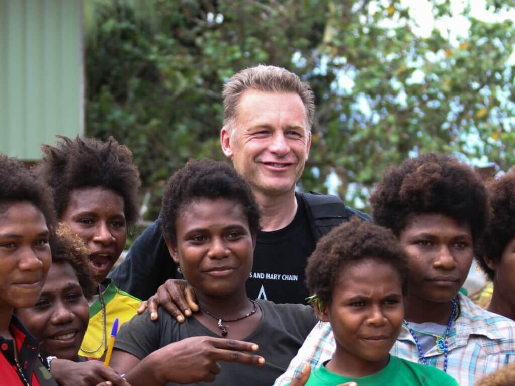 Chris Packham stood smiling with seven young local people.