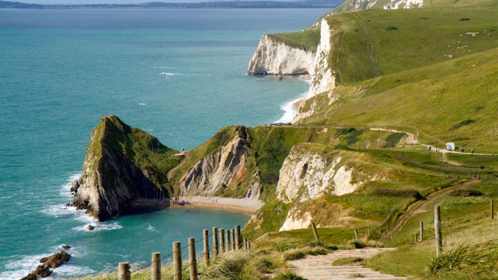 Footpath at the edge of a cliff overlooking blue ocean. South West Coast Path in Dorset