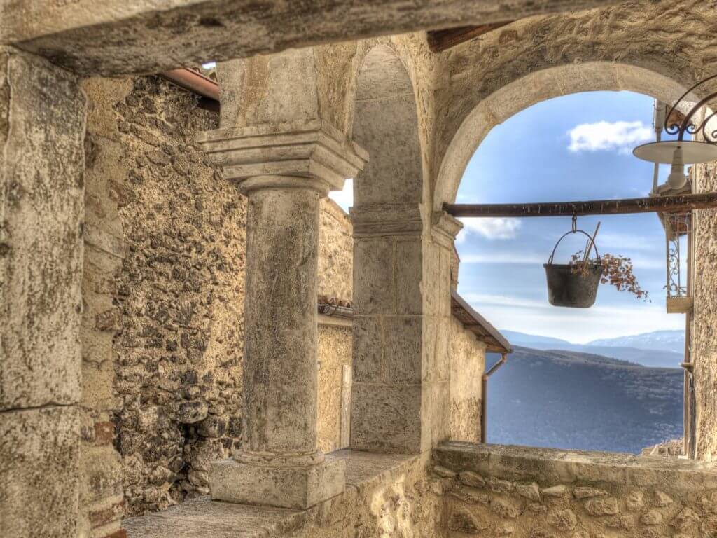 Stone archway with view through to blue skies and mountains.