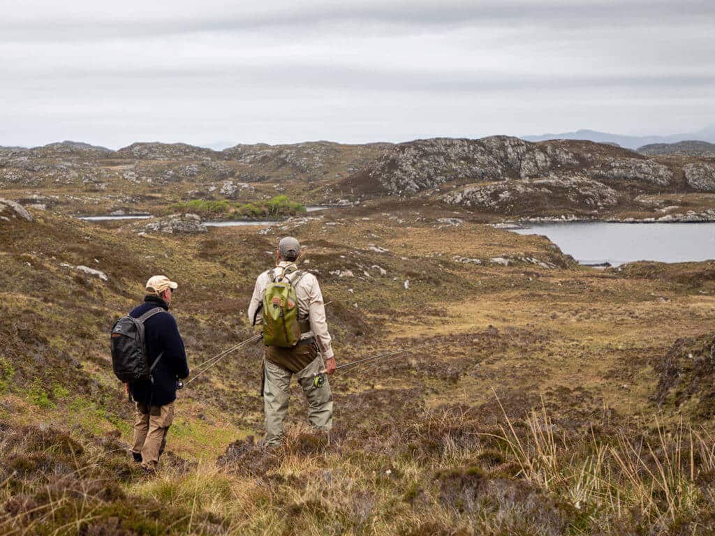 Two fishermen walking towards Loch to go fishing, Assynt, Scotaand