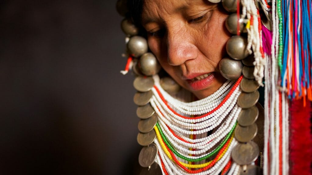 Close up of tribal woman wearing an elaborate headress of colourful beads and coins.