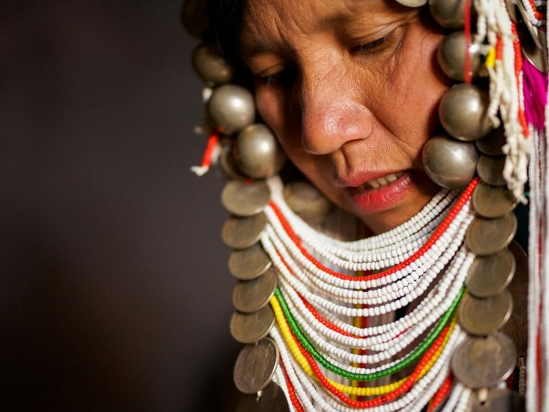 Close up of tribal woman wearing an elaborate headress of colourful beads and coins.