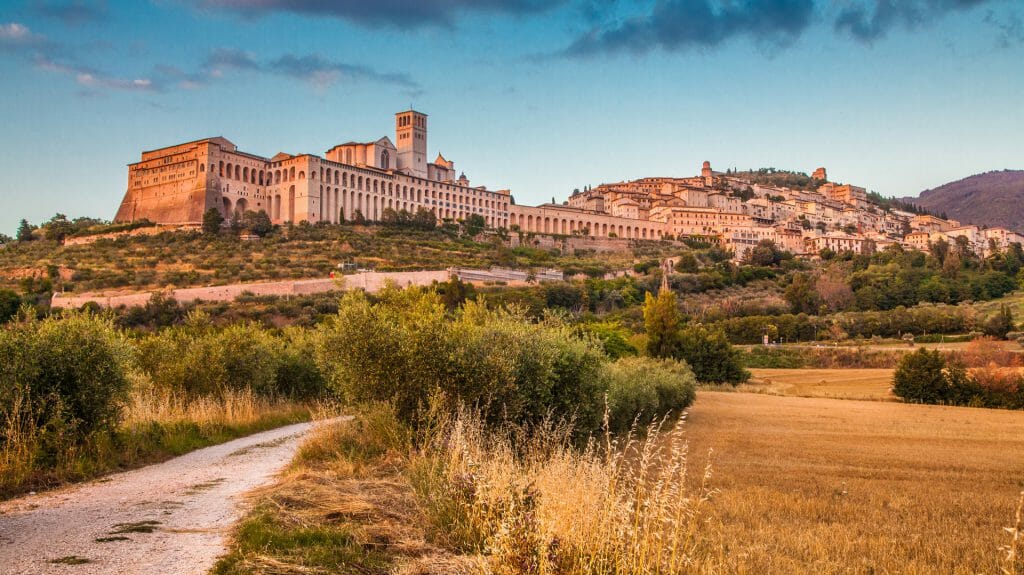 Beautiful view of the ancient town of Assisi with dramatic cloudscape in golden evening light, Umbri