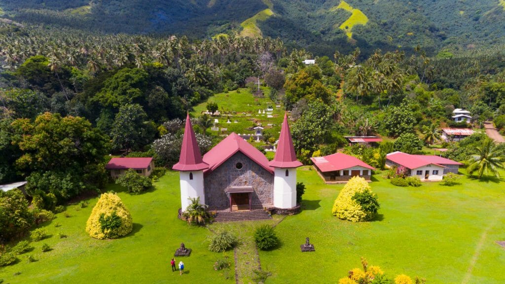 Red roofed church set amidst lush scenery.