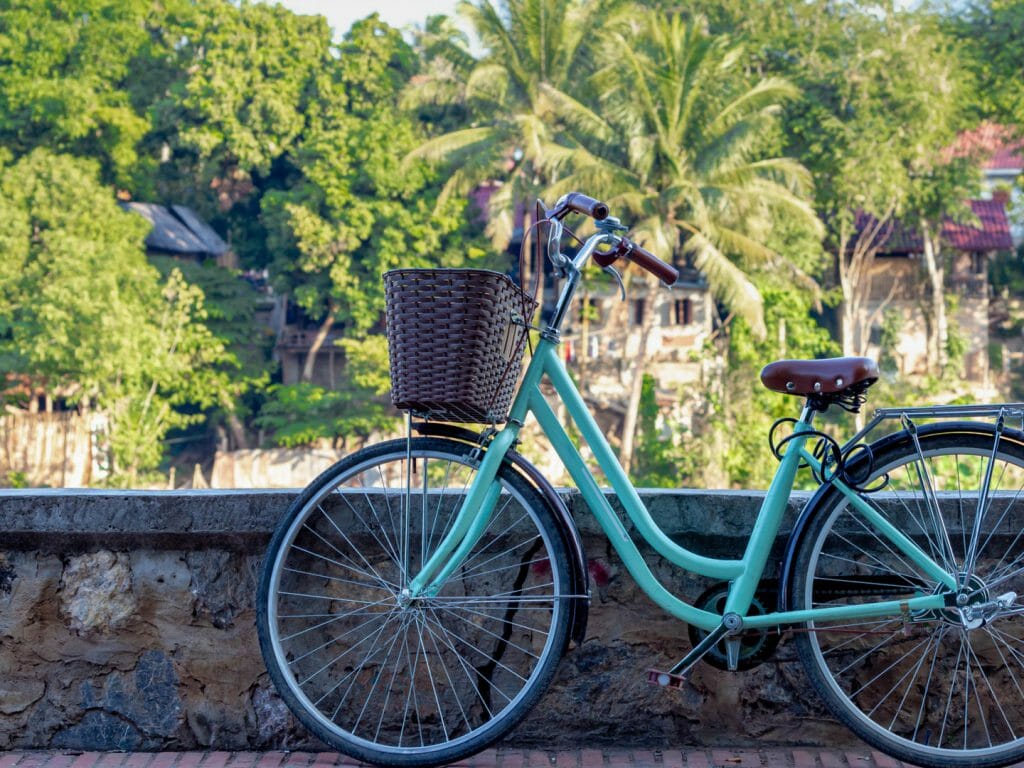 Green bike leant against a low wall with Mekong River on other side.