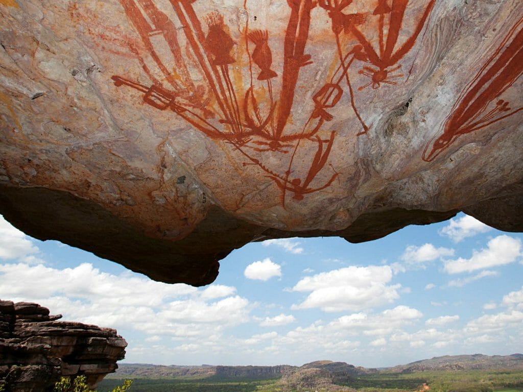Far reaching view stood under overhanging rock covered in aboriginal rock art.
