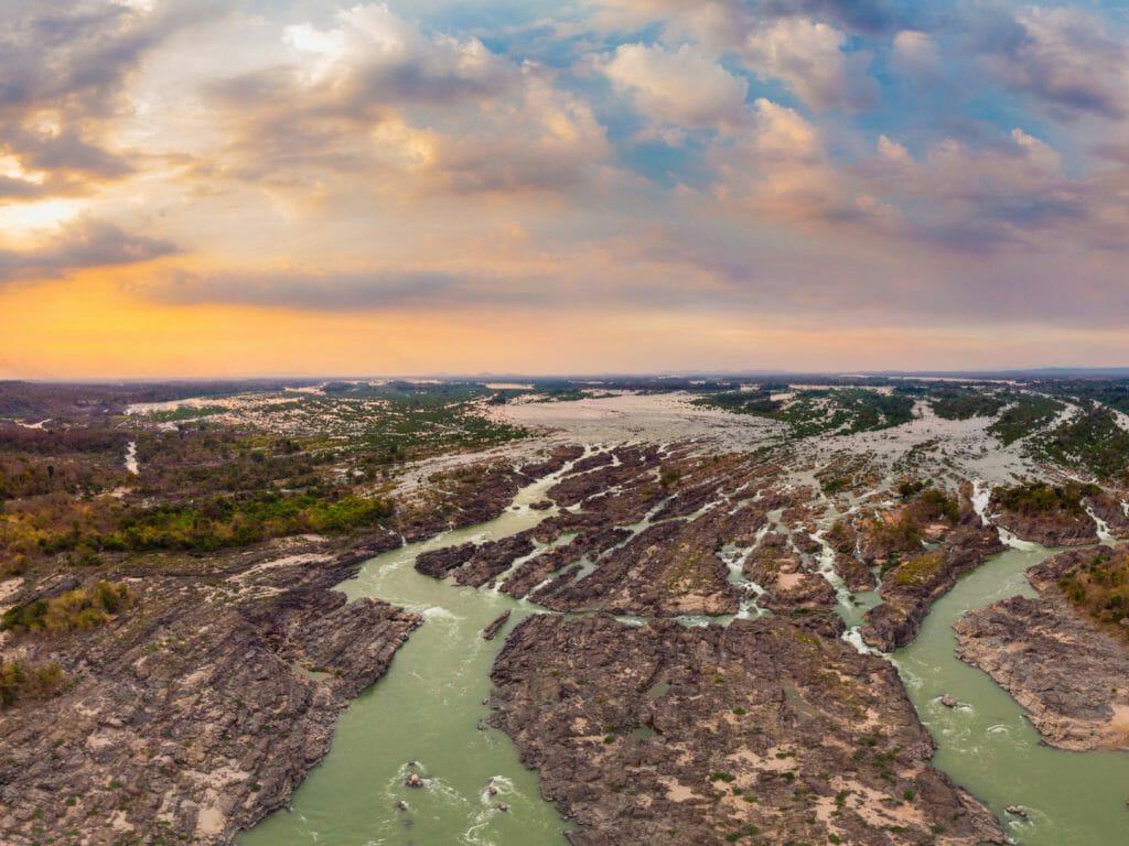 Aerial view of a river delta with many tributaries and jungle covered islets at sunset.