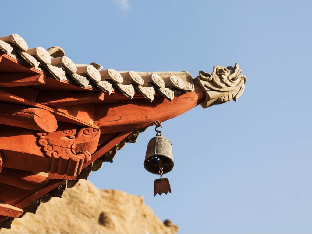 Corner of a traditional Chinese rooftop against blue sky.