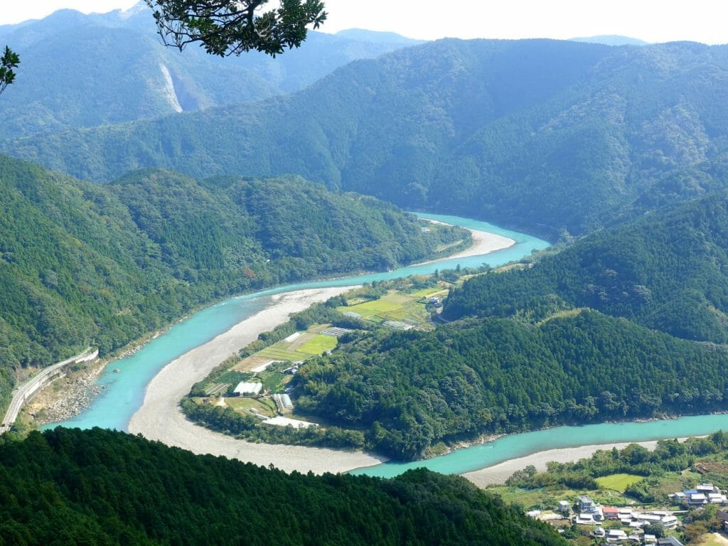 Panoramic aerial view of bending river weaving through lush hills.