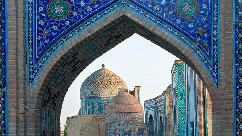 View of Islamic buildings through blue mosaic archway.