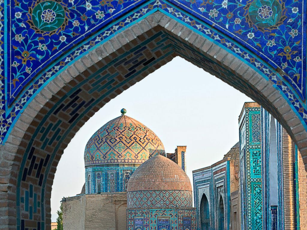 View of Islamic buildings through blue mosaic archway.