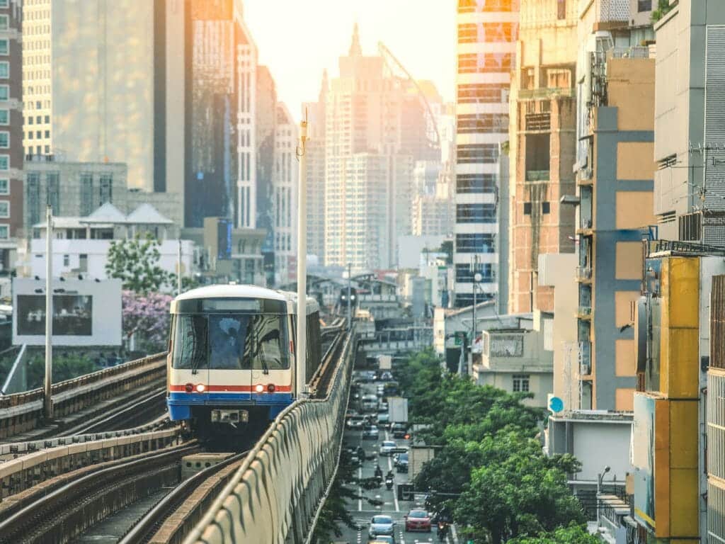 Sky train coming towards the camera with busy Bangkok street below.