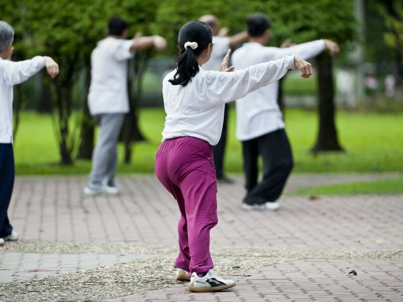 Rear view of local Chinese people doing Tai Chi in the park.