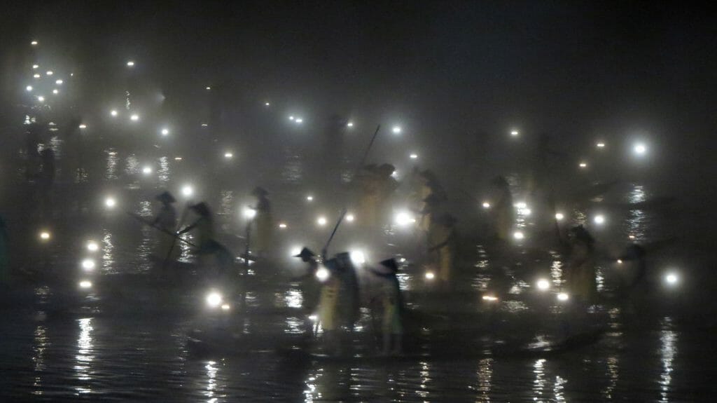 Black and white image of traditional fishermen silhouetted in a light show.