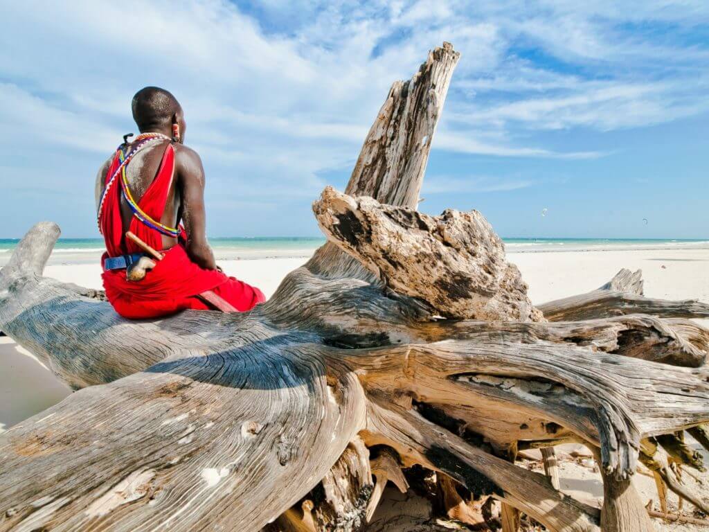 Man of the Maasai tribe sits on the shore of the Indian Ocean