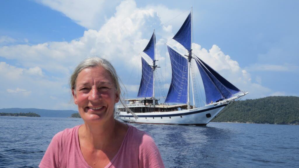 Steppes Travel staff member on the water with blue sailed Seatrek yacht in background.