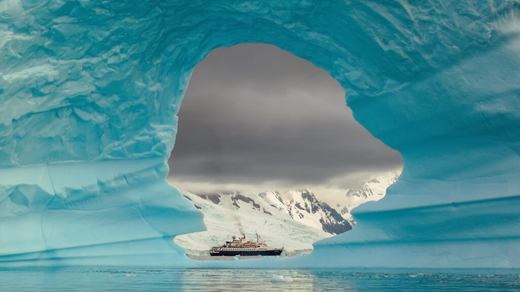 Expedition ship photographed through iceberg, Antarctic Peninsula