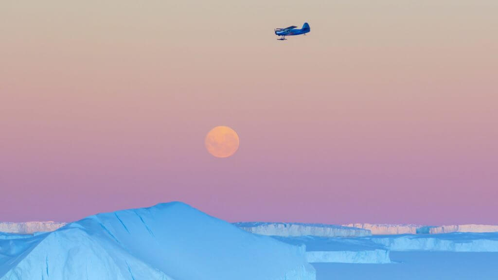 Small plane flying at sunset over Antarctica