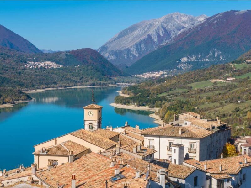 View over pretty village rooftops to turquoise lake and mountains beyond.