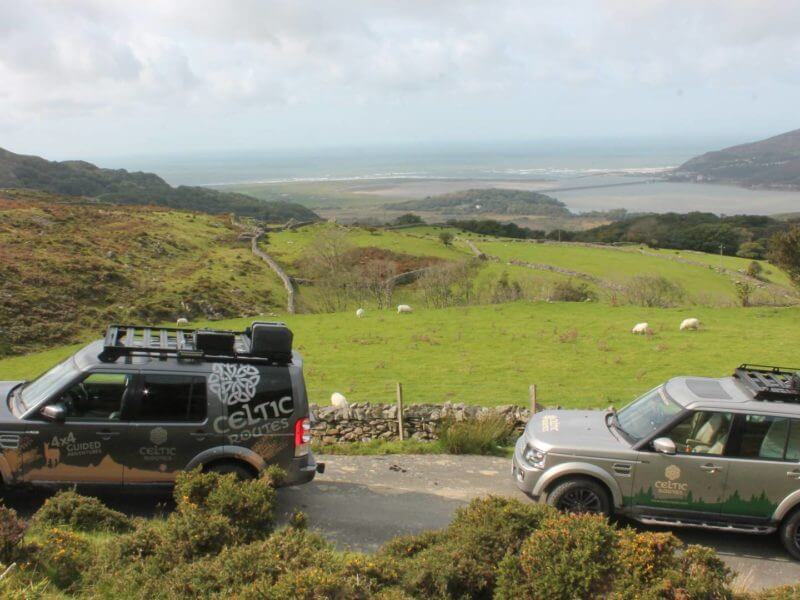 Land Rovers driving past bay, Wales
