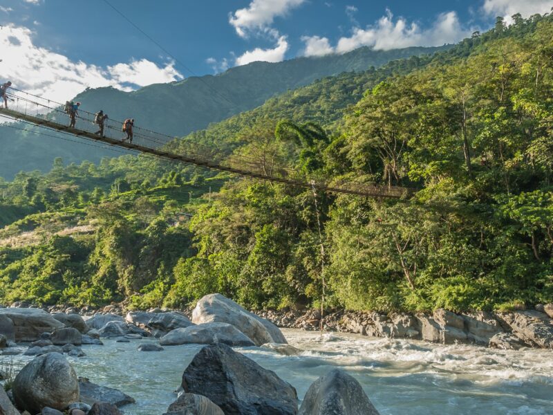 Walkers crossing river by bridge, Annapurna Circuit, Nepal