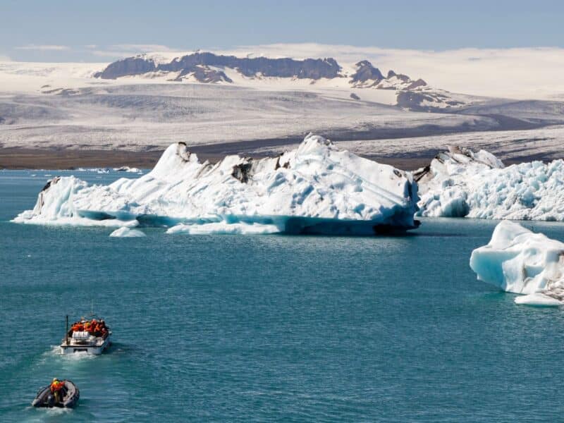 Boats on lagoon heading towards icebergs, Iceland