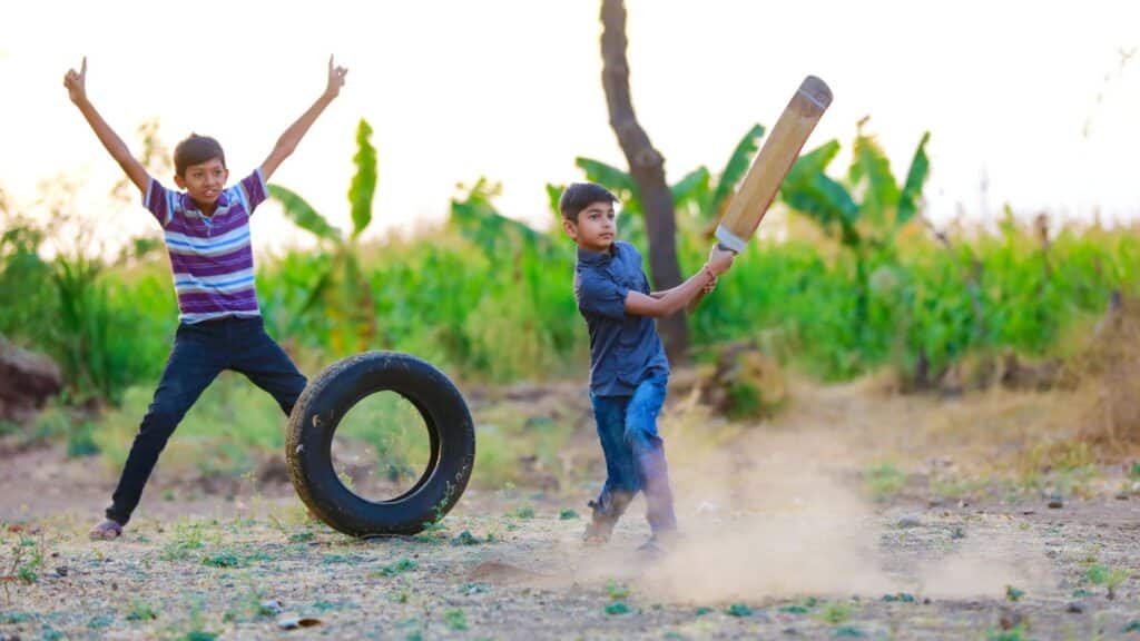 Two boys playing rural cricket, India